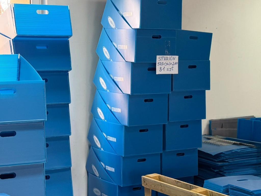 Stacks of blue corrugated plastic boxes in a production area.