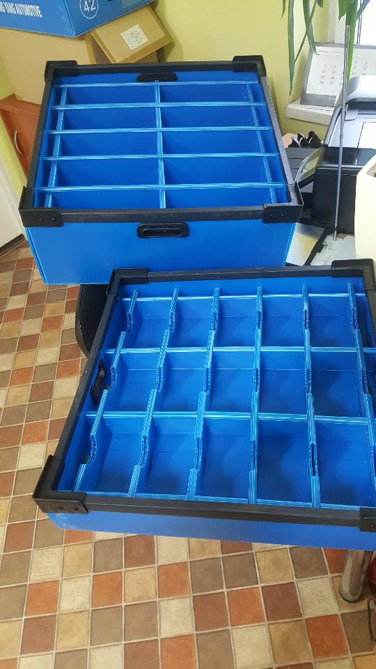 Black corrugated plastic box with custom foam dunnage holding automotive lighting assemblies.