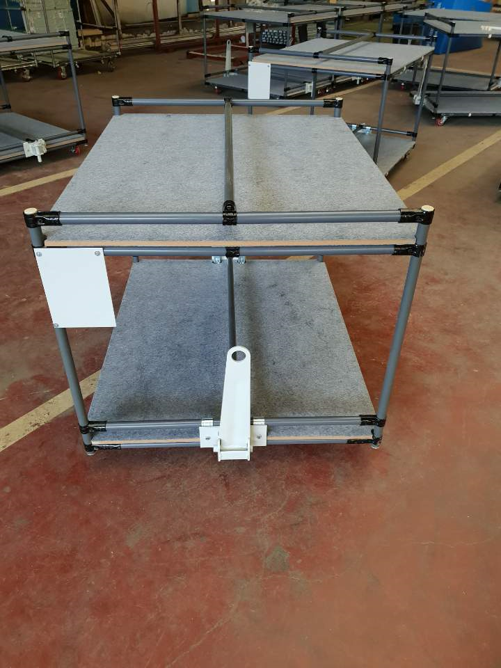 Two-level industrial trolley built from pipe framing with felt-lined shelves and a tow hitch.