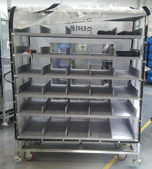 Multi-tier mobile rack with corrugated plastic dividers and protective mesh sides on heavy-duty casters.