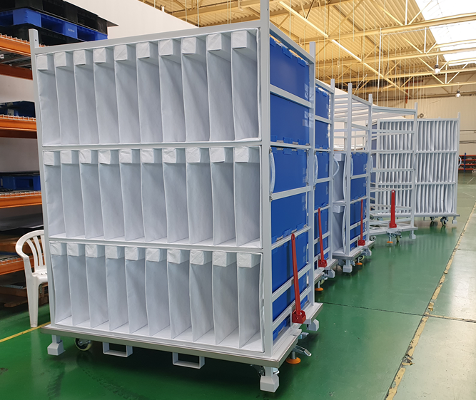 Industrial trolleys with soft vertical dividers and blue corrugated plastic side panels on a green shop floor.