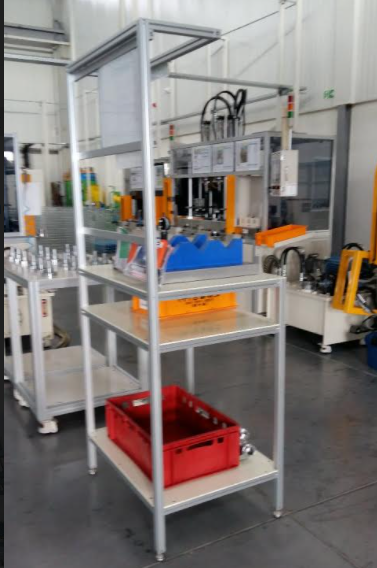 Aluminum-profile assembly station with jigs, part bins, and tools beside production equipment.